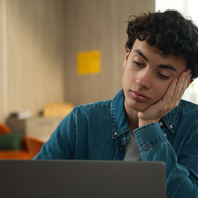Junger Azubi sitzt traurig vor dem Laptop