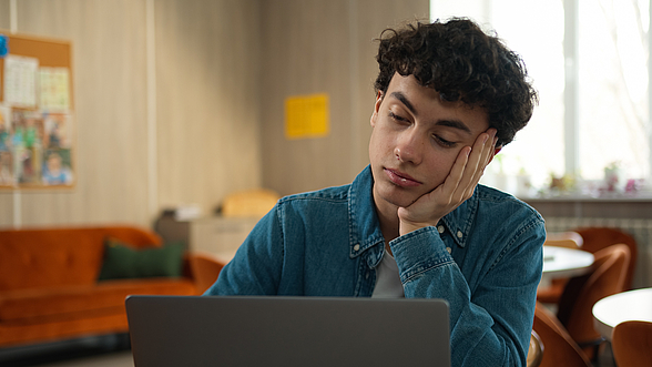 Auszubildender blickt erschöpft auf seinen Computer.