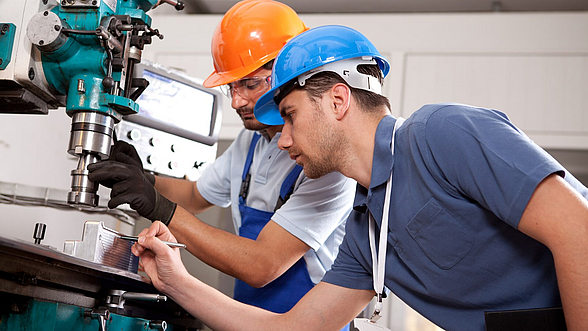 © fatihhoca - istock.com Zwei Männer arbeiten an einer Metallfräse