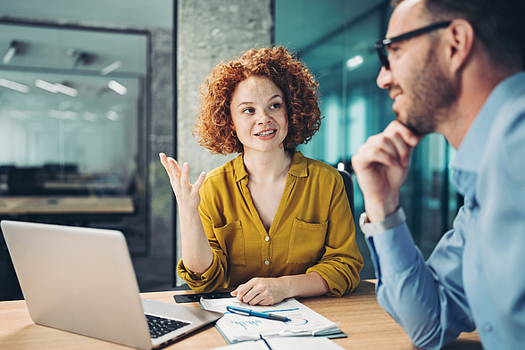 Zwei Personen sitzen im Büro und besprechen sich