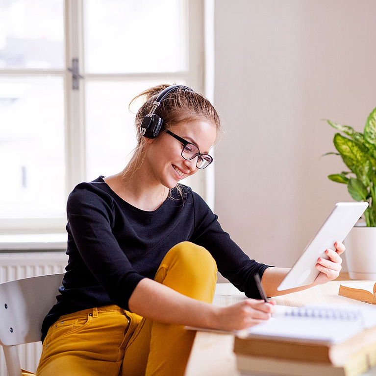 Junge Frau sitzt am Laptop und nimmt an einer digitalen Lerneinheit teil.