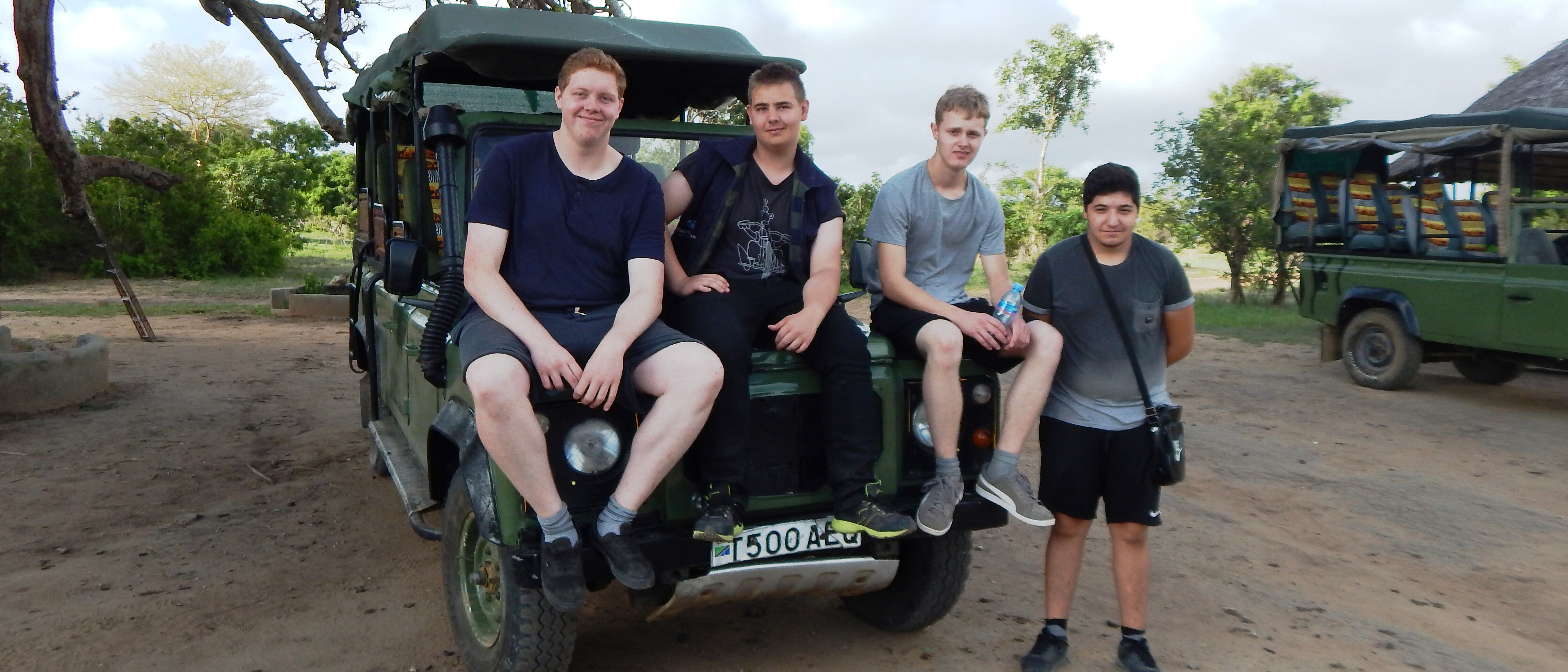 Mehrere Azubis sitzen und stehen auf Malta um einen Jeep herum.