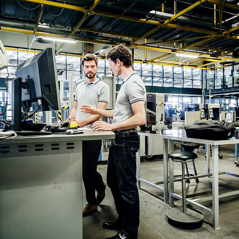 Zwei Ingenieure unterhalten sich in einer Produktionshalle