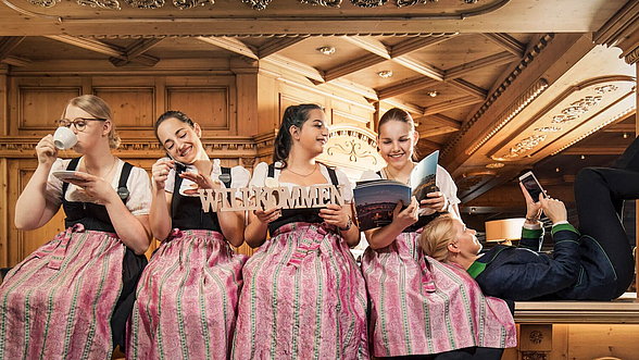 Frauen im Drindl sitzen an einer Hotelrezeption