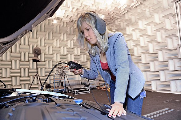 Zu sehen ist eine Mitarbeiterin von Carcoustics mit Kopfhörern. Sie befindet sich in einem Tonstudio.