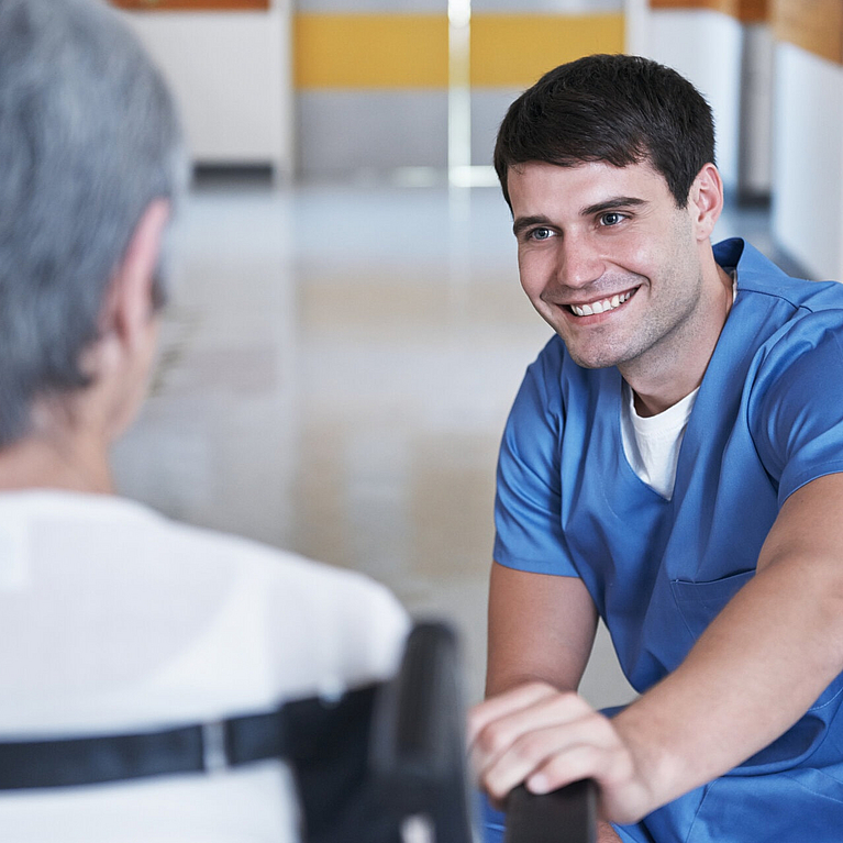 Pfleger kümmert sich um ältere Dame im Rollstuhl