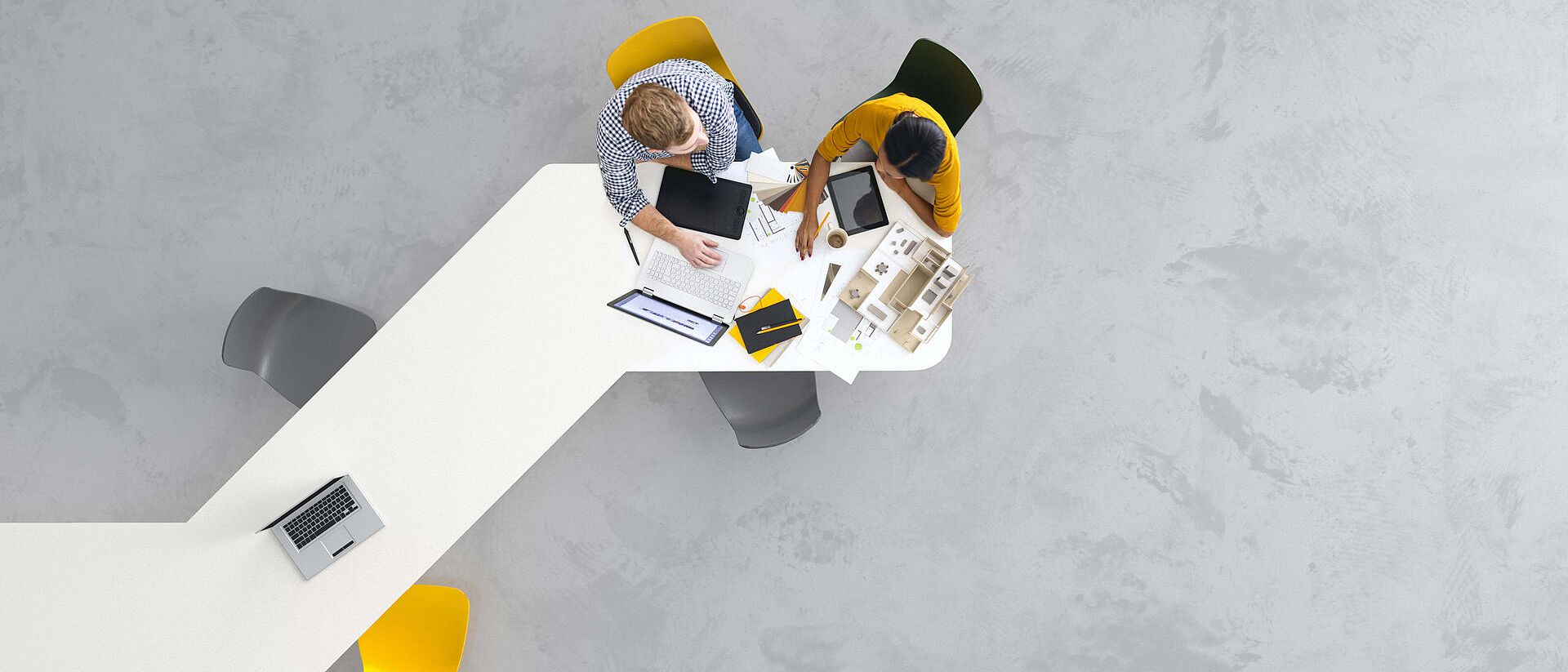 Perspektive von oben: Zwei Personen sitzen an einem Schreibtisch