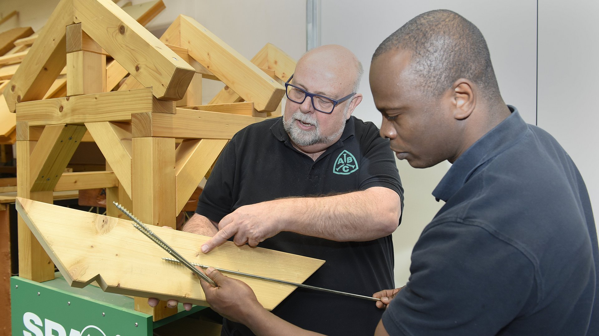 Aboubakar Fofana und Hans-Jürgen Barth arbeiten an einer Holzplatte.