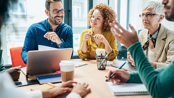 Kollegen sitzen im Besprechungsraum und unterhalten sich
