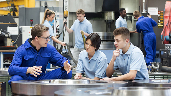 ©  Manuel Tauber-Romieri – istock.com Angestellter erklärt zwei jungen Menschen seinen Beruf.