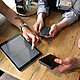 Azubis und Ausbilder beim Gespräch. Man sieht die technischen Geräte Tablet und Smartphone, über die das Berichtsheft gepflegt wird.
