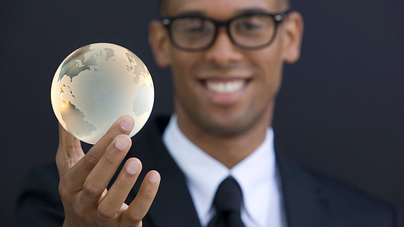© gettyimages Ein Mann hält eine Weltkugel in der Hand