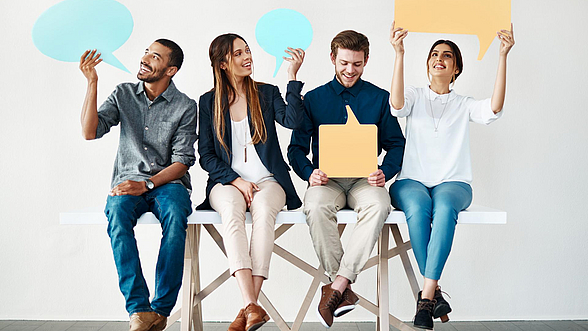 Zwei Männer und zwei Frauen halten Sprechblasen hoch.