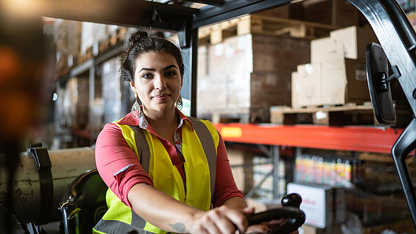 Portrait einer jungen Frau, die auf einem Gabelstapler sitzt