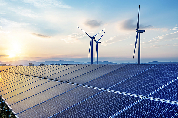 Eine PV-Anlage und im Hintergrund Windkraftanlagen.