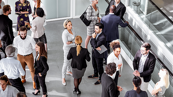 © sanjeri – istock.com  Menschen stehen in Gruppen zusammen und unterhalten sich.