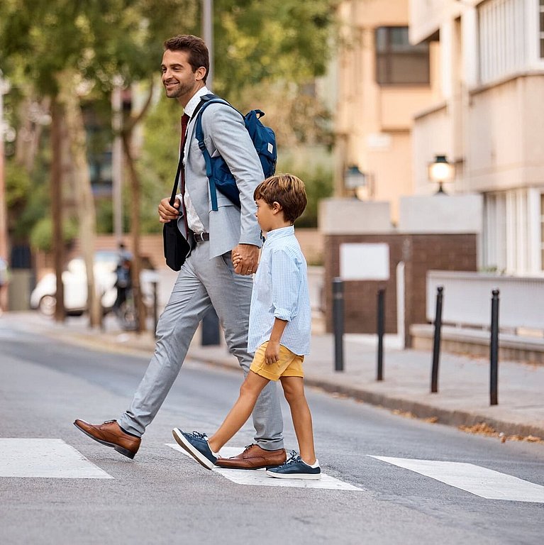 Ein Vater läuft mit seinem Sohn über die Straße.