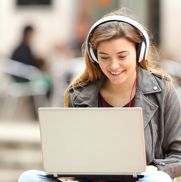 Junge Frau mit Kopfhörer und Laptop