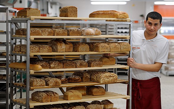 Zakaria Dahmoun neben einem Regal voller Brote