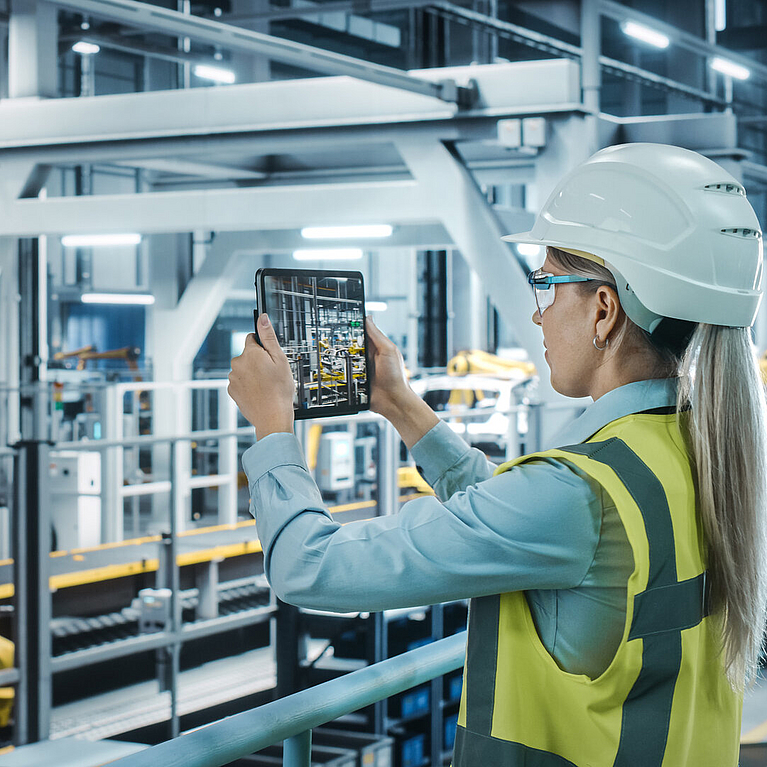 © gorodenkoff - istock.com Junge Frau mit Schutzhelm und Tablet in Produktionshalle