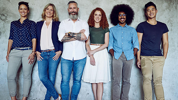 Menschen unterschiedlichen Geschlechts, Alters und Hautfarbe stehen nebeneinander.