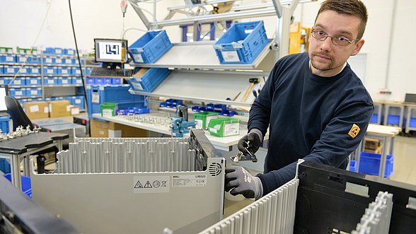 David Sattler schraubt in der Werkshalle Computergehäuse zusammen.