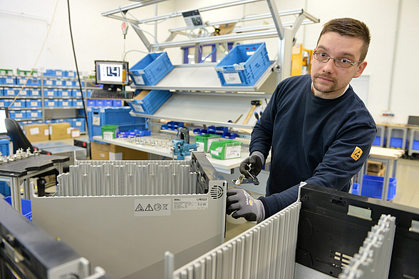 David Sattler schraubt in der Werkshalle Computergehäuse zusammen.