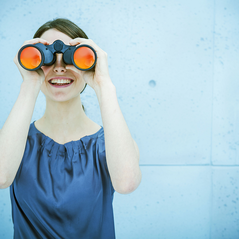 Frau hat ein Fernglas in der Hand und hält Ausschau 