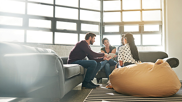Mehrere Personen sitzen in einer Sitzecke zusammen und unterhalten sich