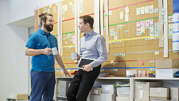 © alvarez - istock.com Zwei Personen unterhalten sich in der Produktionshalle