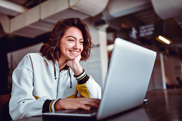 Junge Frau schaut sich etwas auf dem Laptop an