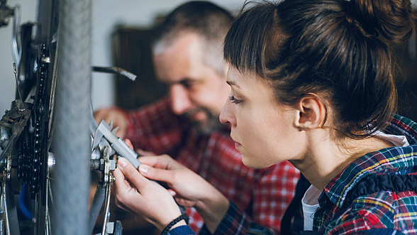 Eine Handwerkerin und ein Handwerker bei der Arbeit.