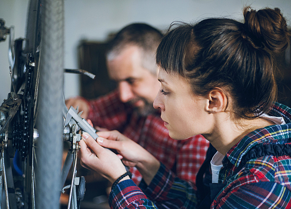 Eine Handwerkerin und ein Handwerker bei der Arbeit.